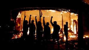Manifestantes posam do lado de fora de loja de bebidas em chamas nos Estados Unidos